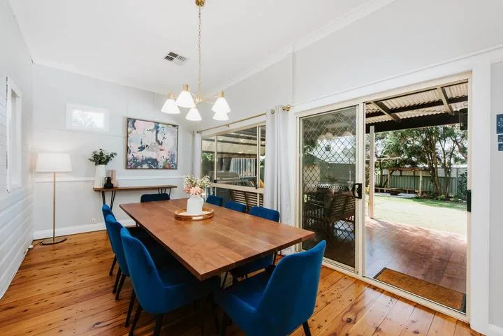 A dining area with a wooden table and sliding glass doors opening to a patio.