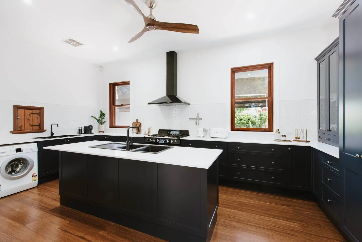 Una cocina moderna con gabinetes oscuros, una isla central y una lavadora.