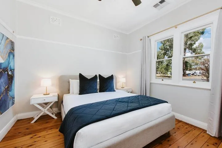 A bedroom with a bed dressed in white and dark blue bedding.