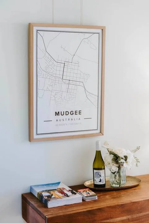 A framed map hangs above a wooden table with books and flowers.