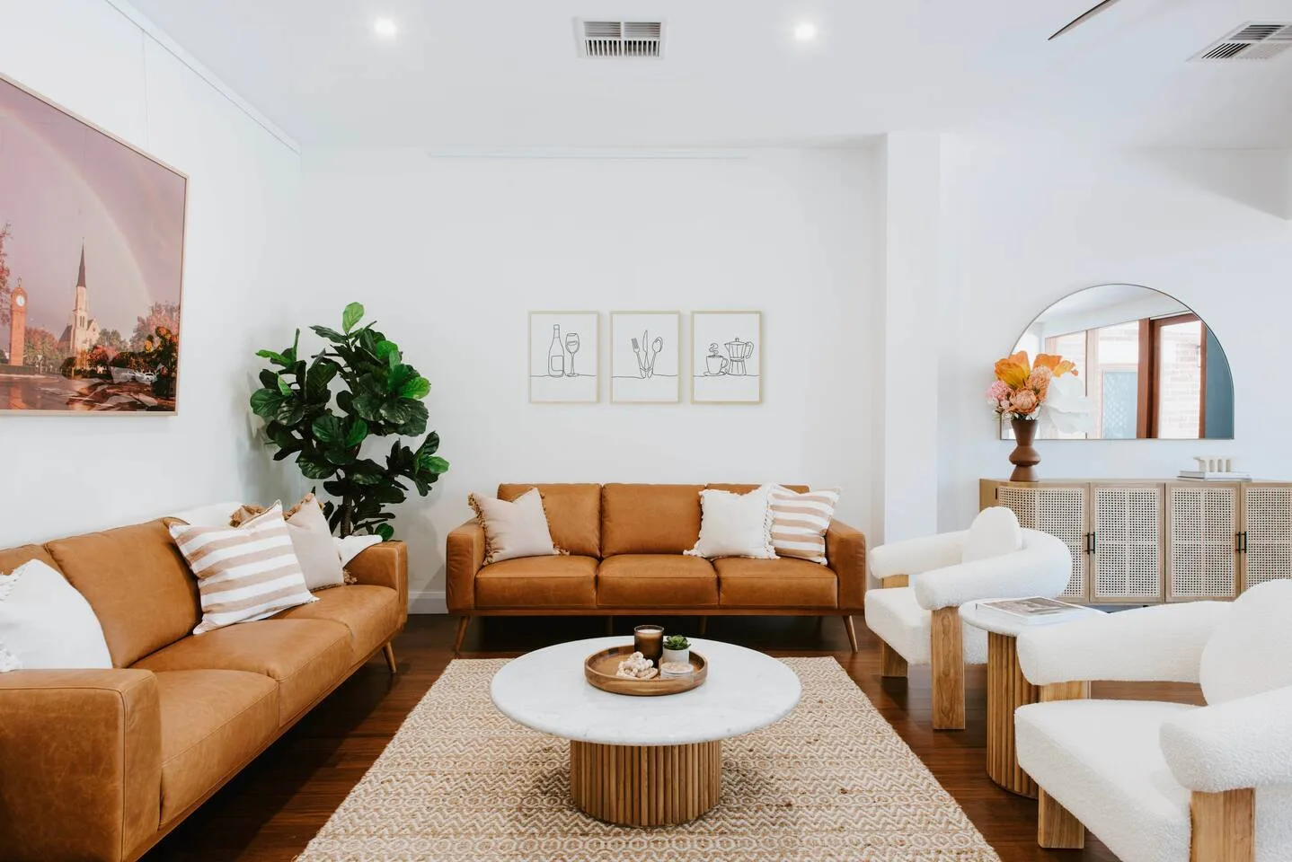 A living room with sofas and a round coffee table arranged on a rug.