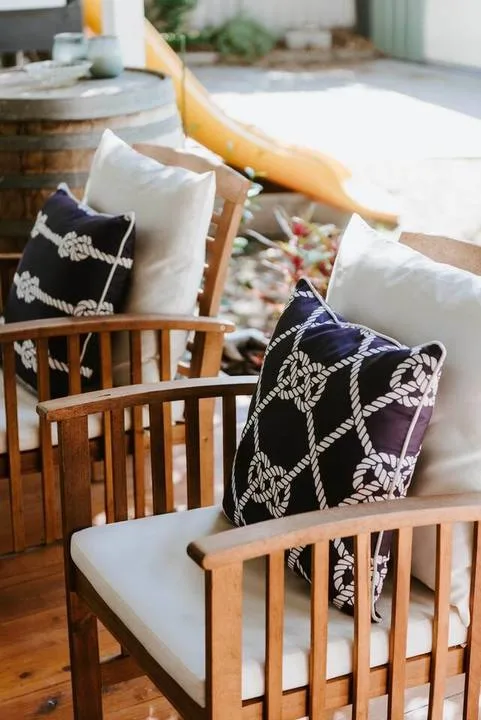Wooden outdoor seating with light cushions and patterned pillows sits beside a curved slide.