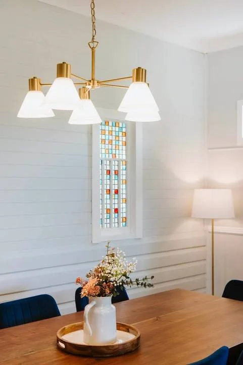 A dining area with a wooden table, floral centerpiece, and pendant light.