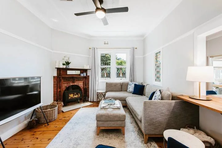 A bright living room with a seating area, fireplace, and television.