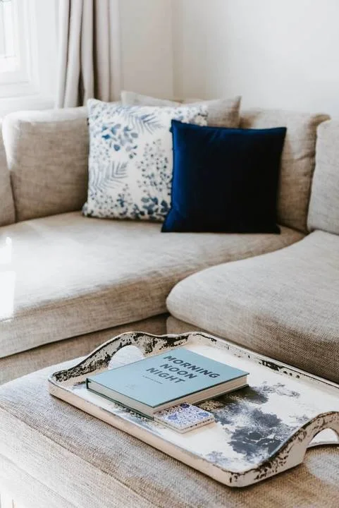 A light-colored seating area with patterned cushions and a book on a tray.