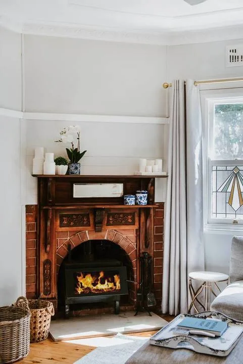 A bright living room features a brick fireplace and a large window.