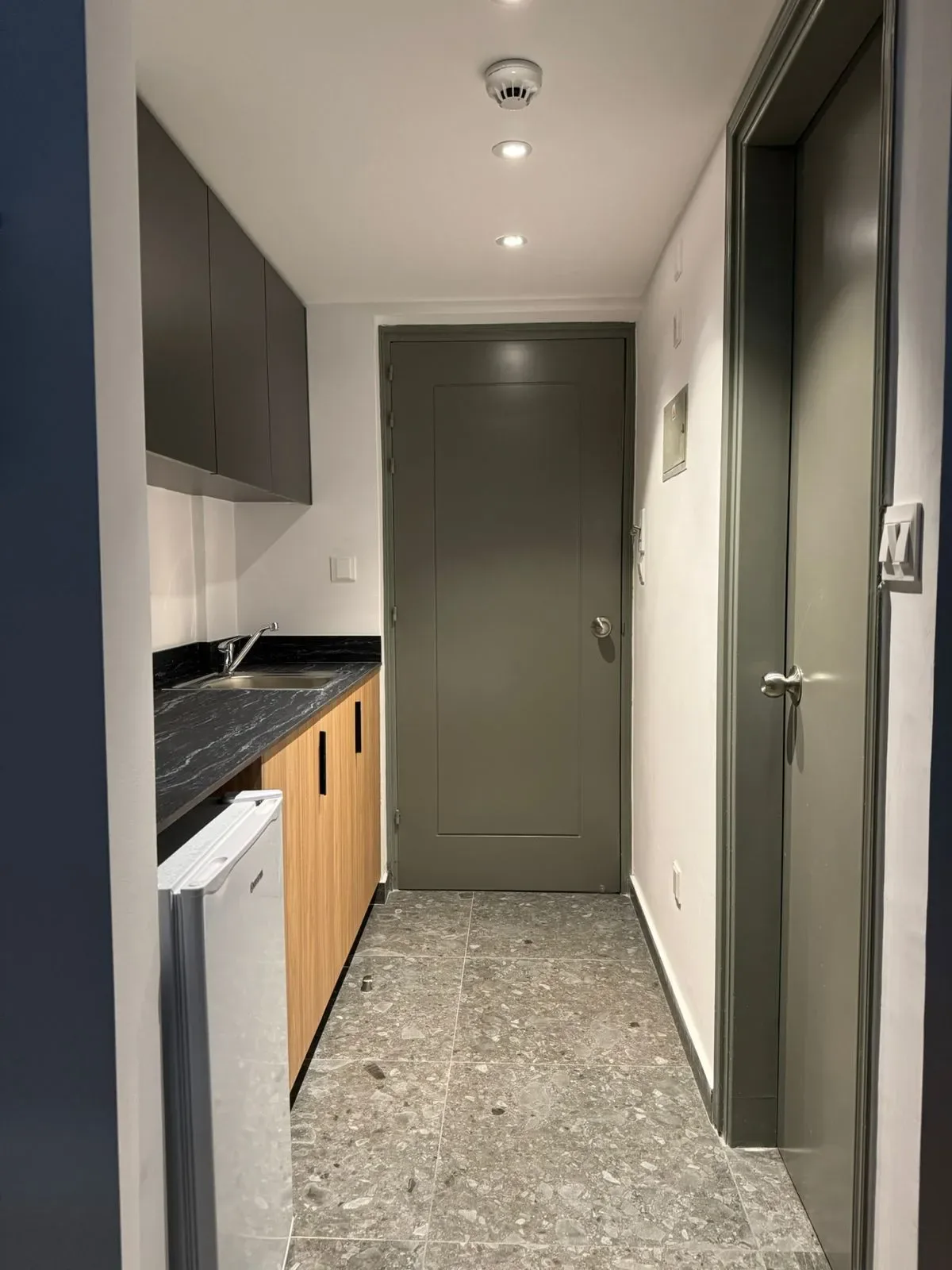 Cocina con fregadero, refrigerador, armarios y puerta.