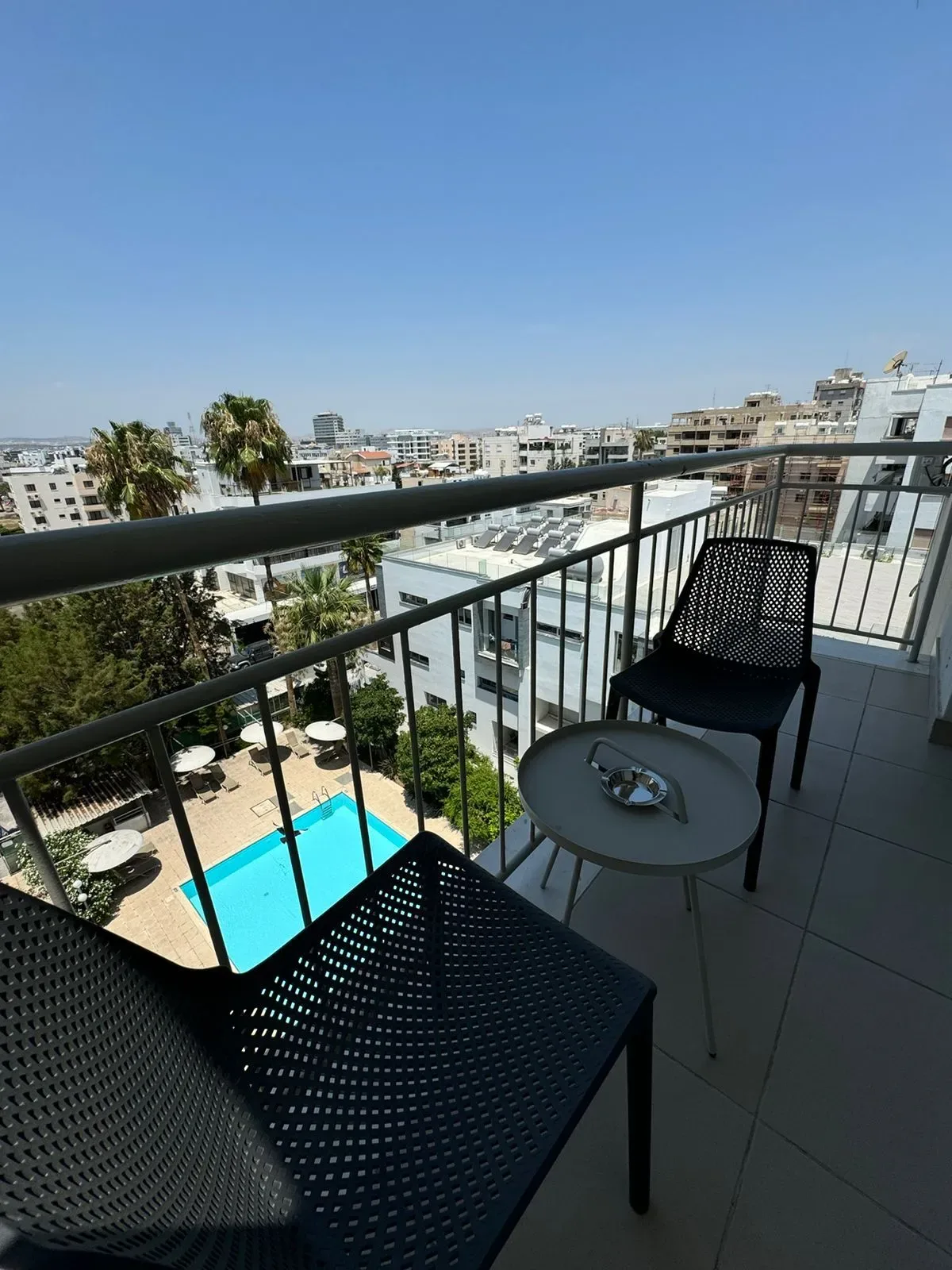 Balcón con mesa y sillas con vistas a una piscina.