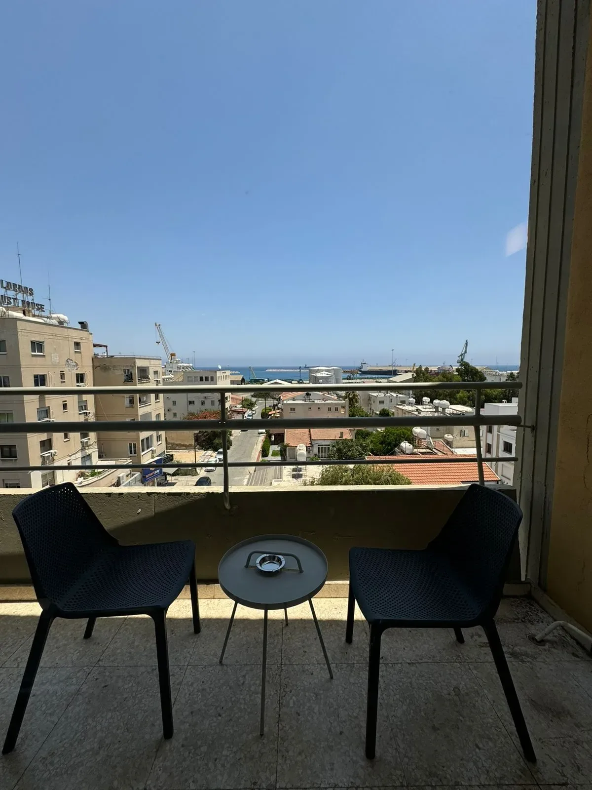 Balcón con dos sillas y una mesa con vistas a la ciudad.