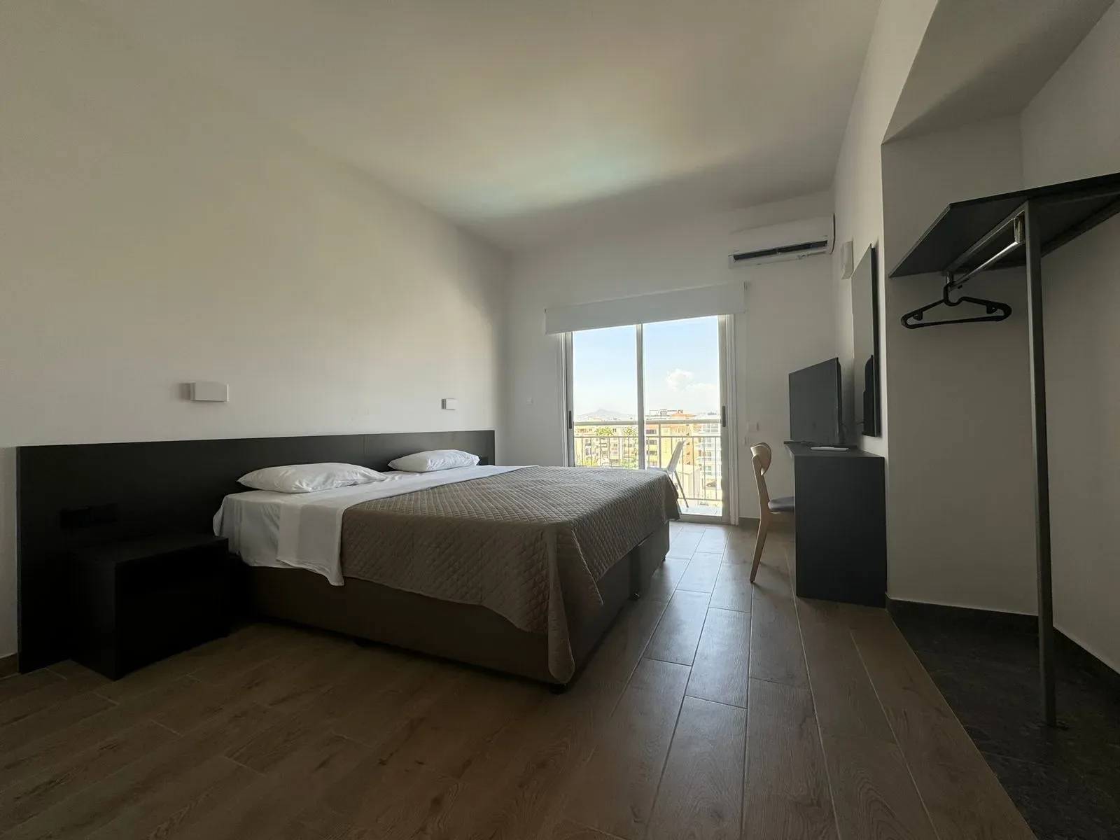 Habitación de hotel con una cama grande y una puerta corredera de cristal.