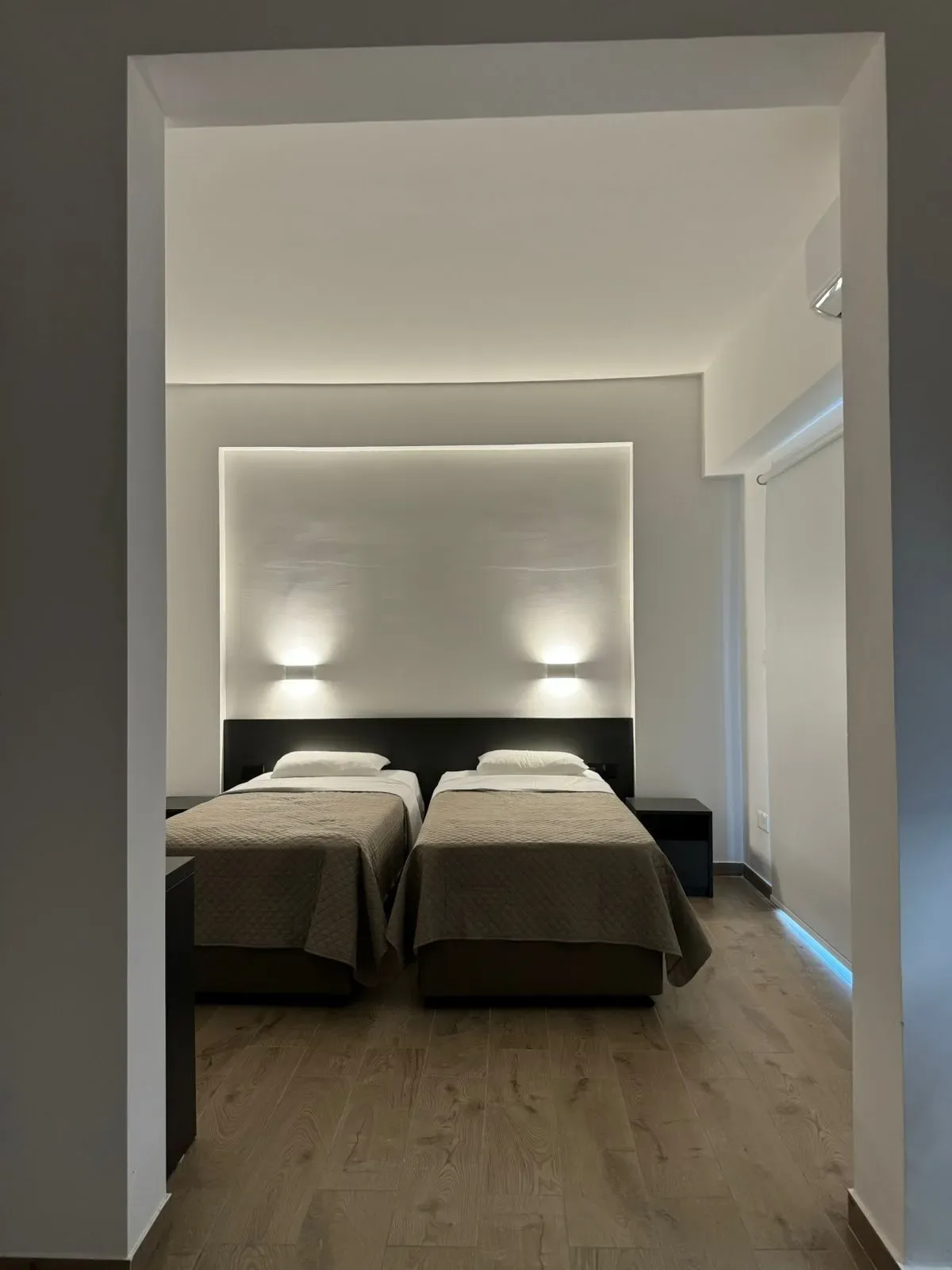 Habitación de hotel con dos camas y suelo de madera.