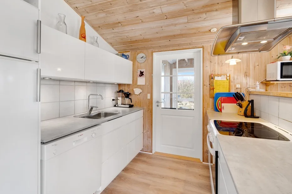 Una cocina compacta con gabinetes blancos, un fregadero y una placa de cocción.