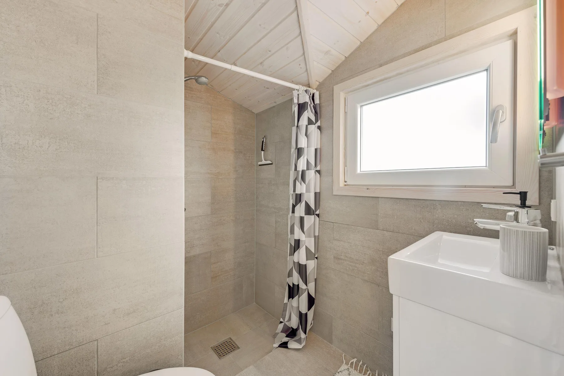 Un baño con ducha, lavabo y ventana.