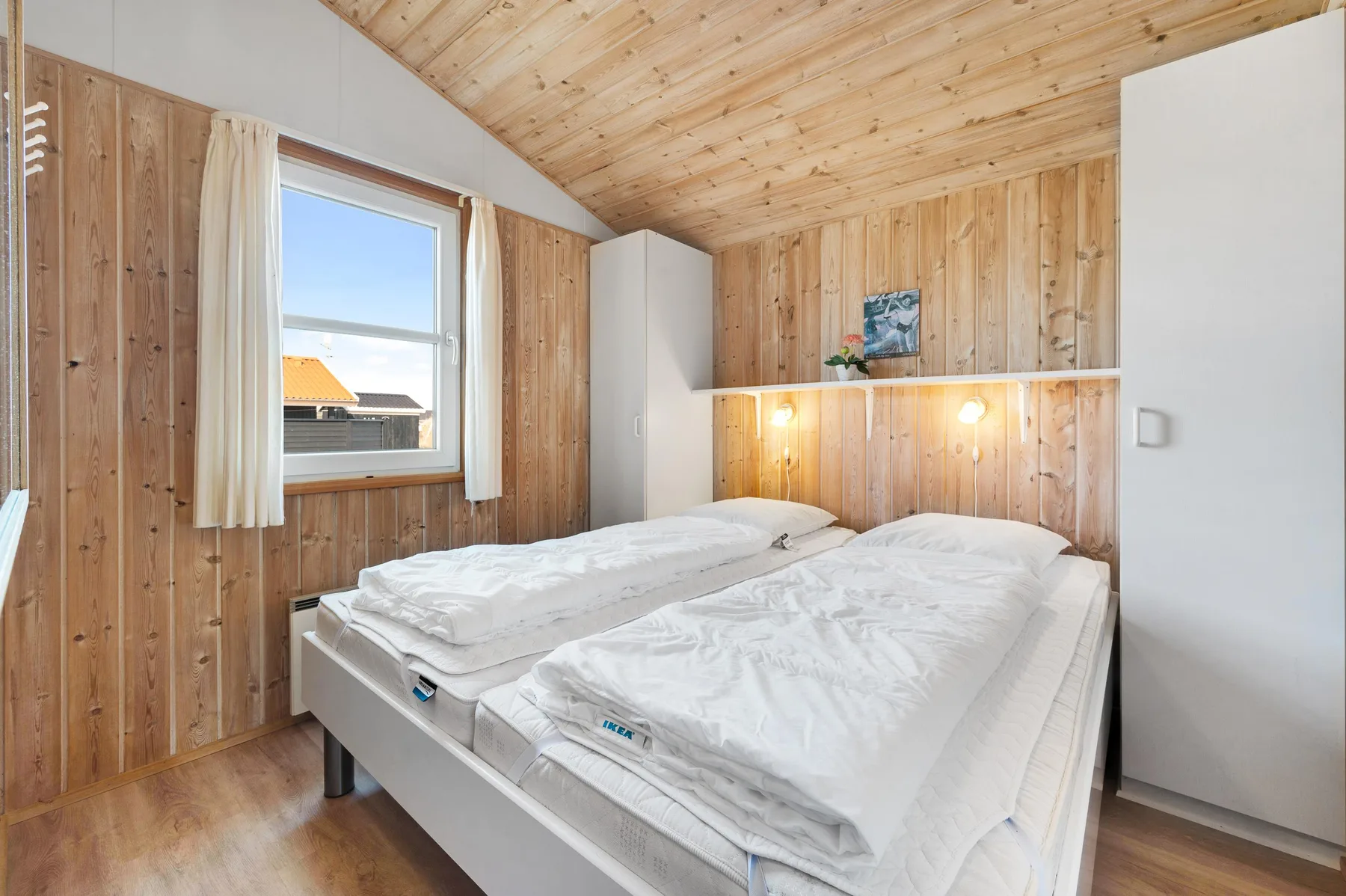 Un dormitorio con dos camas bajo un techo inclinado revestido de madera.