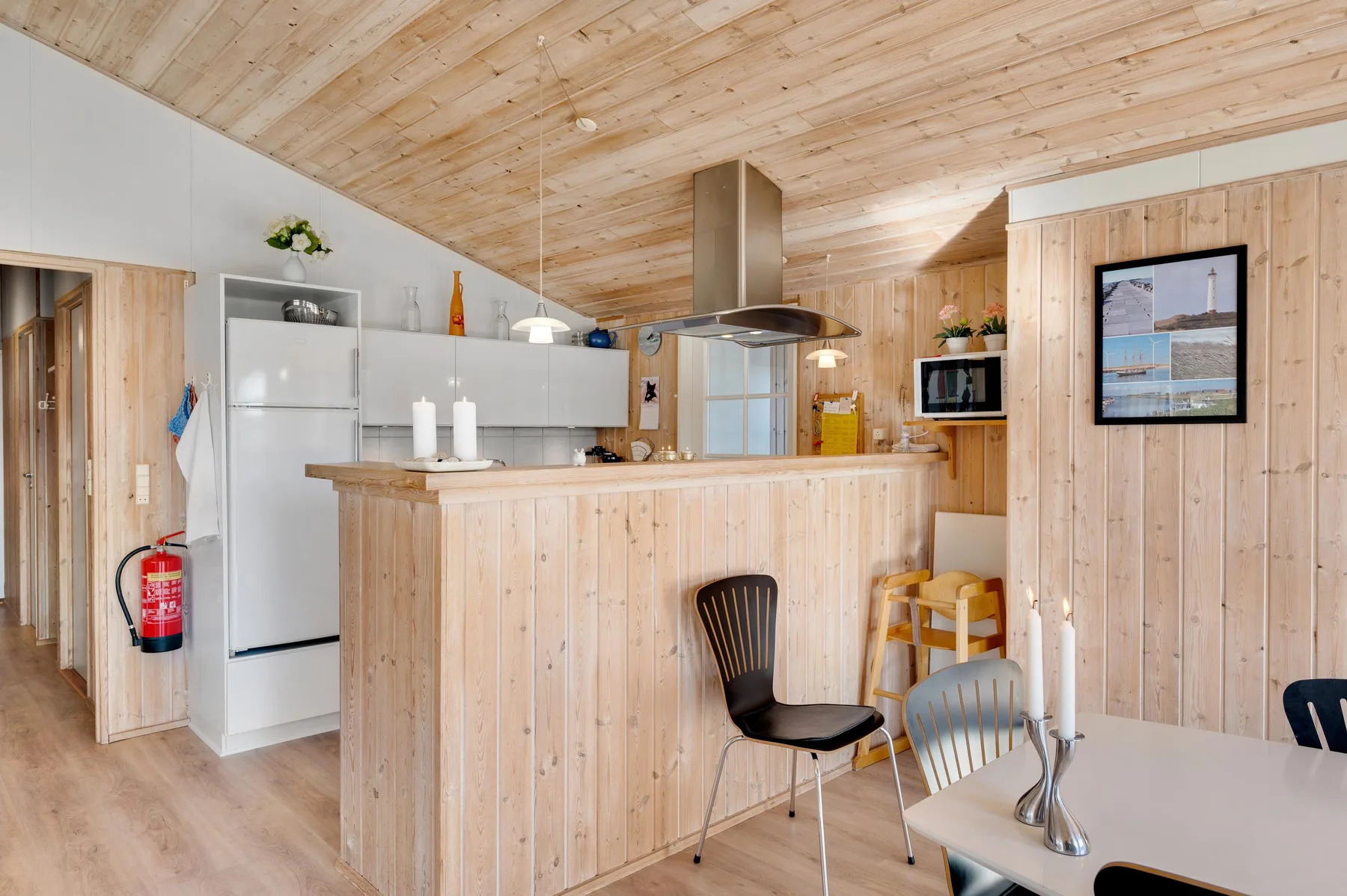 Cocina y comedor revestidos de madera, con una isla central y una mesa.