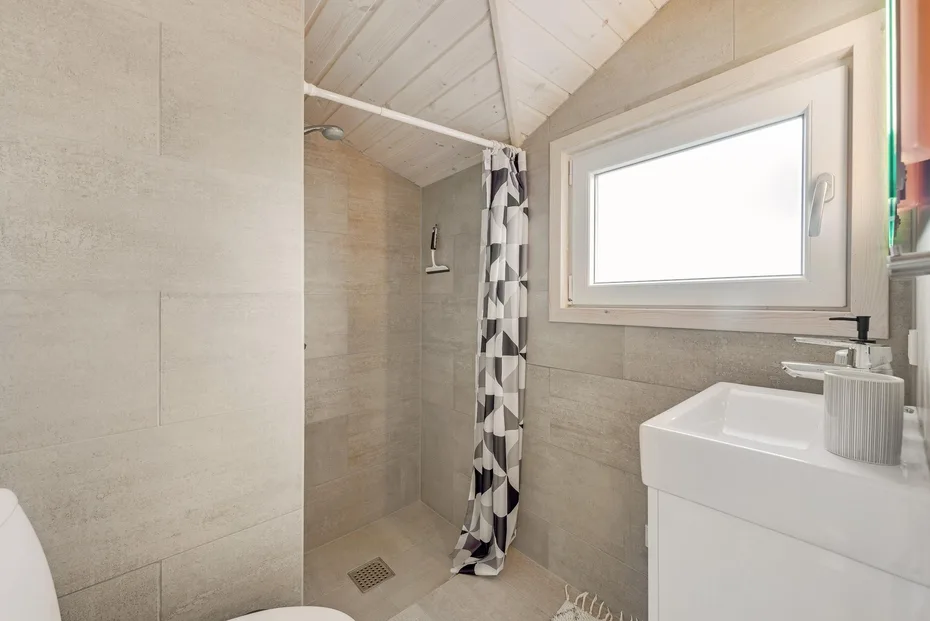 Un baño con ducha, cortina estampada y ventana.