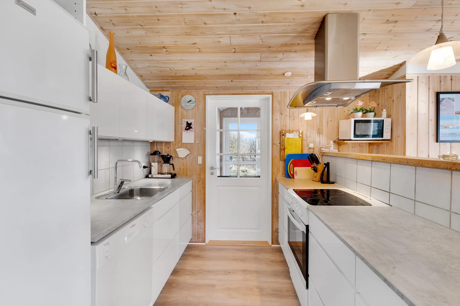 Una cocina luminosa con armarios blancos, encimeras y electrodomésticos.
