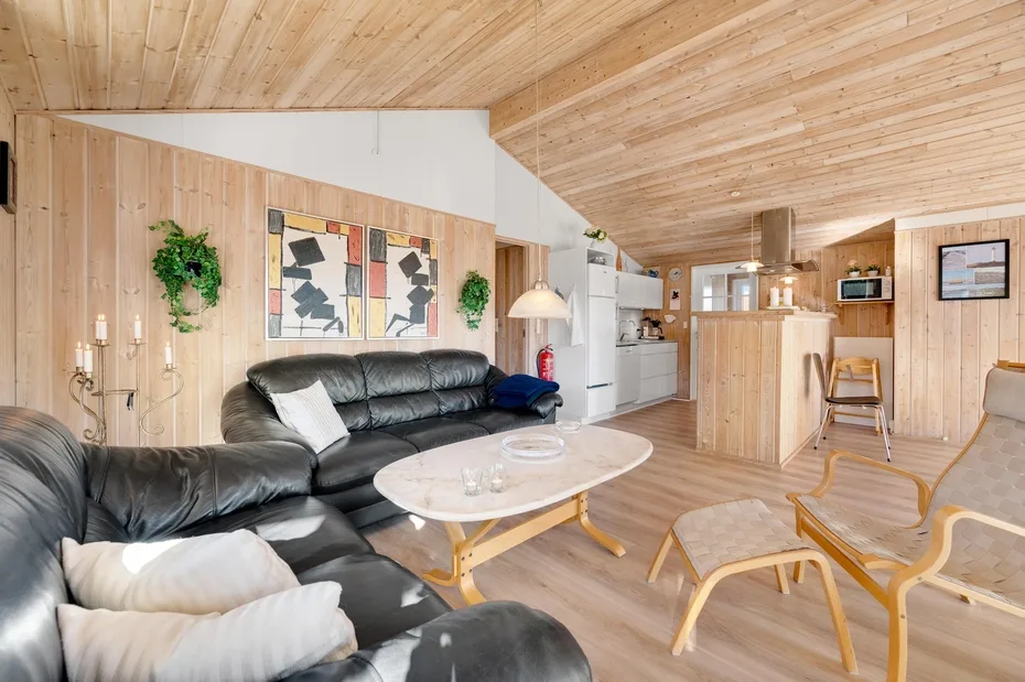 Una sala revestida de madera con asientos de cuero y una cocina abierta.