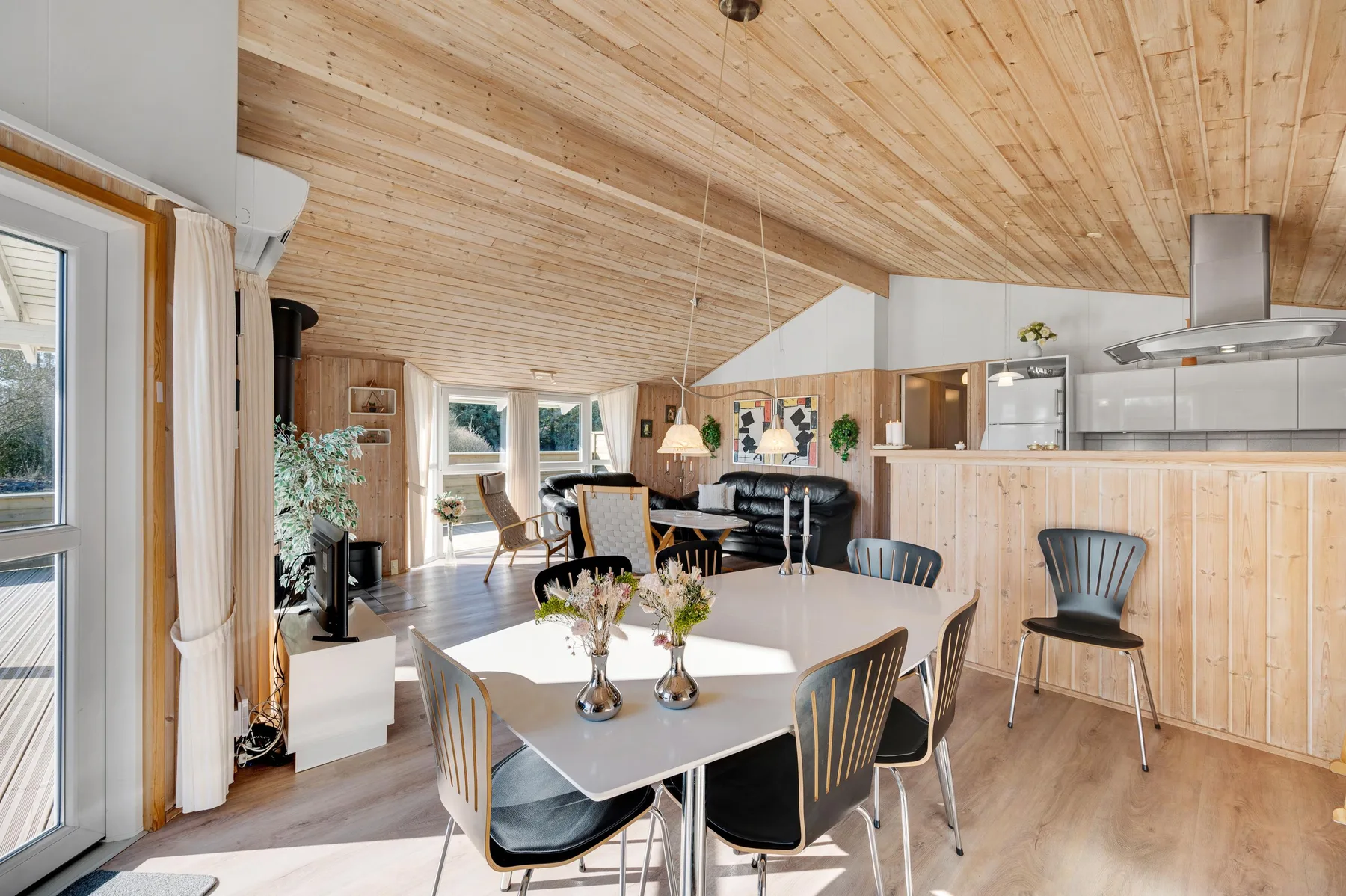 Zona diáfana de comedor y cocina con una mesa larga y asientos alrededor.