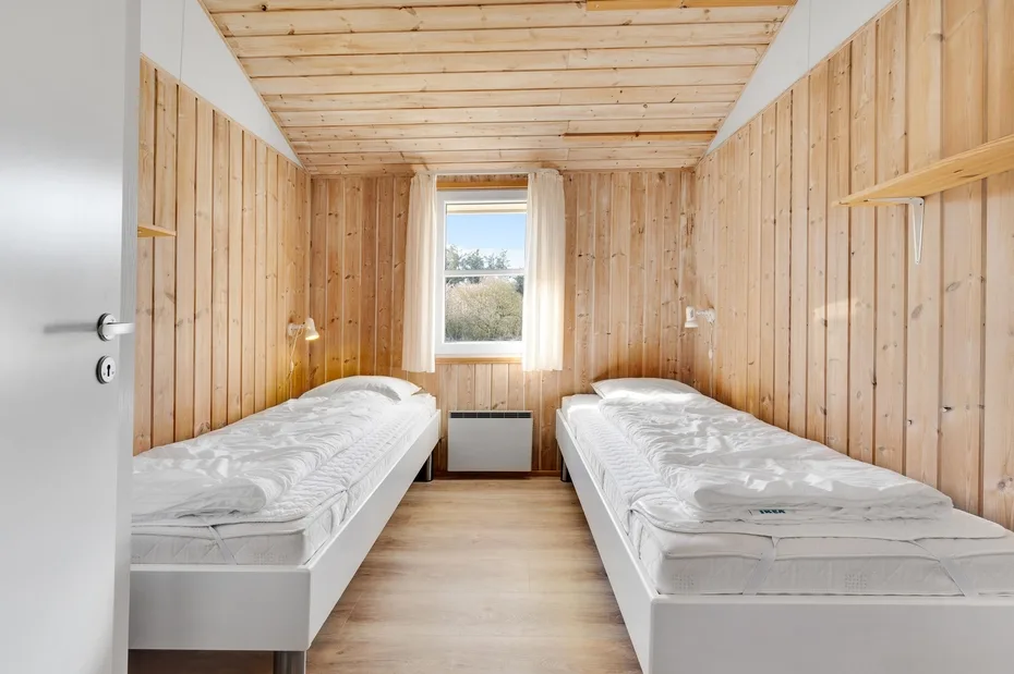 Un dormitorio con dos camas individuales y una ventana al fondo.