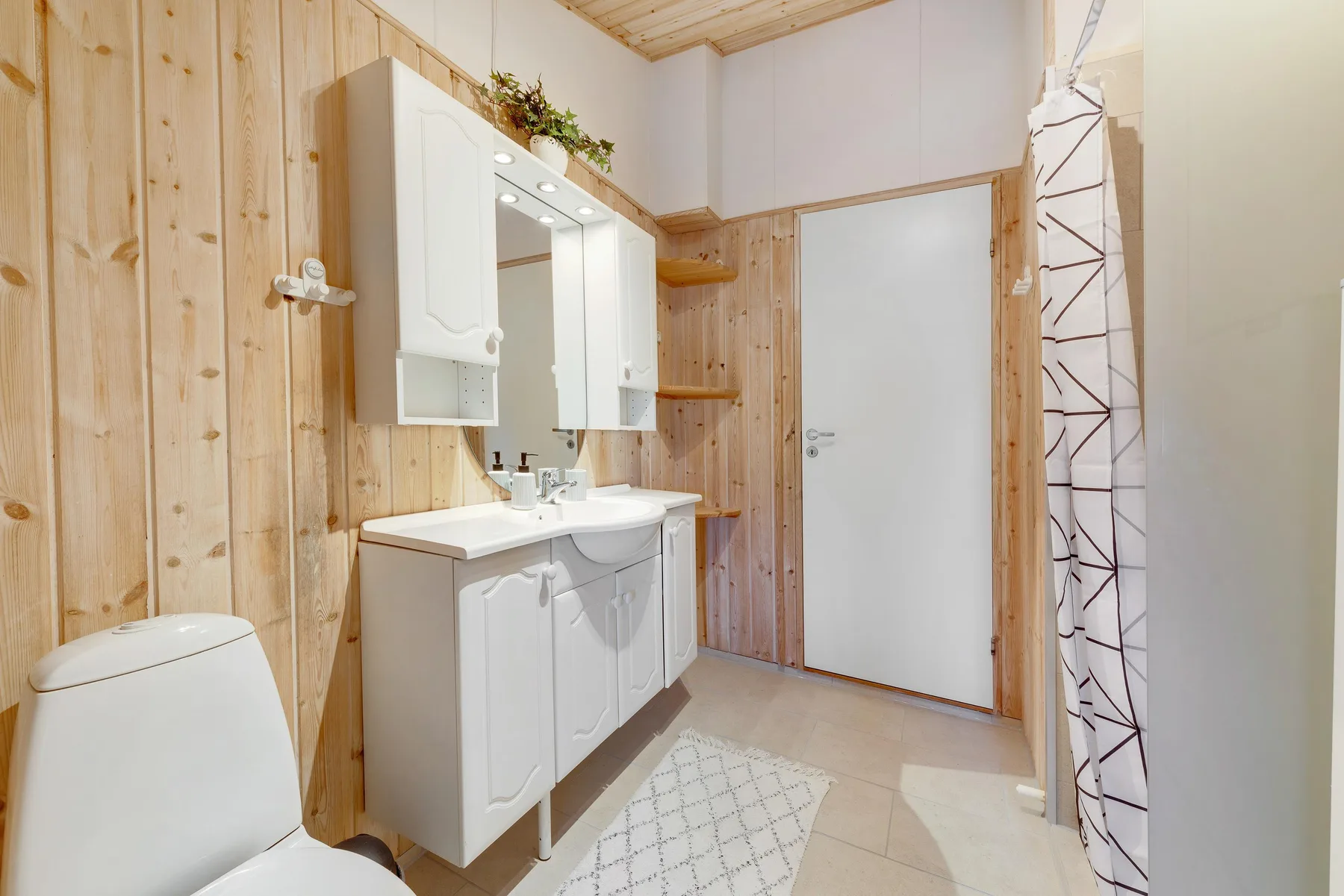 Un baño con lavabo blanco, inodoro y cortina de ducha.