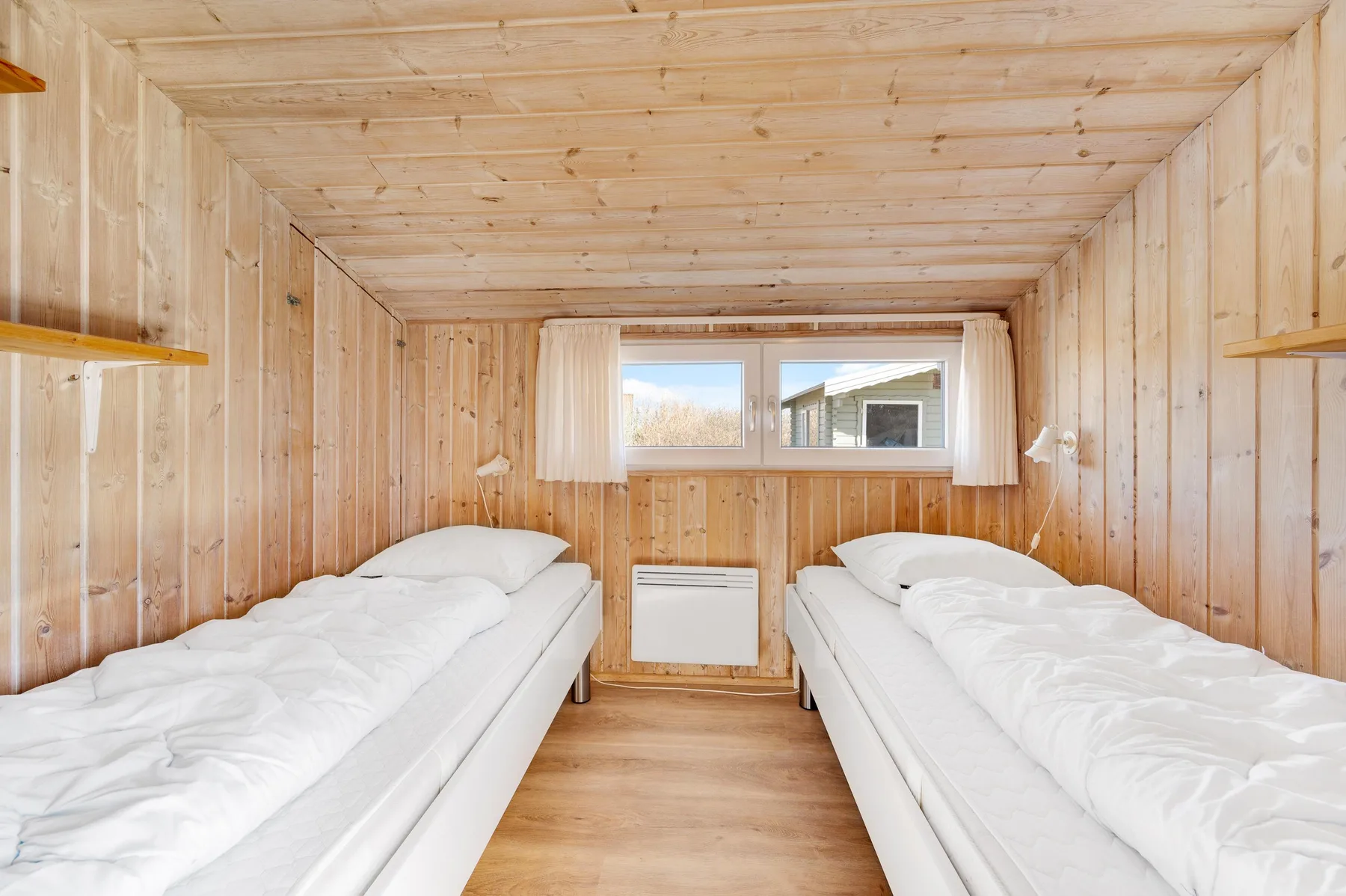 Un dormitorio con dos camas y una ventana al fondo.