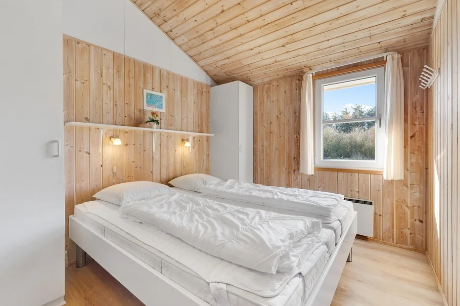 Un dormitorio con dos camas bajo un techo de madera inclinado y una ventana.