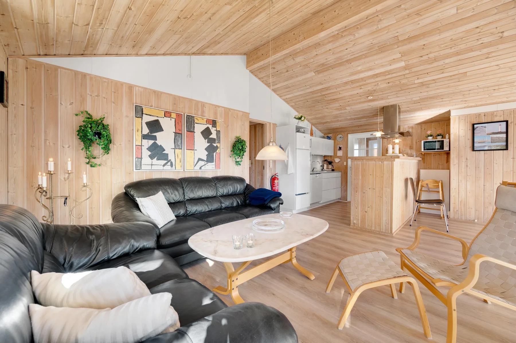 Una sala revestida de madera con asientos oscuros y cocina abierta.