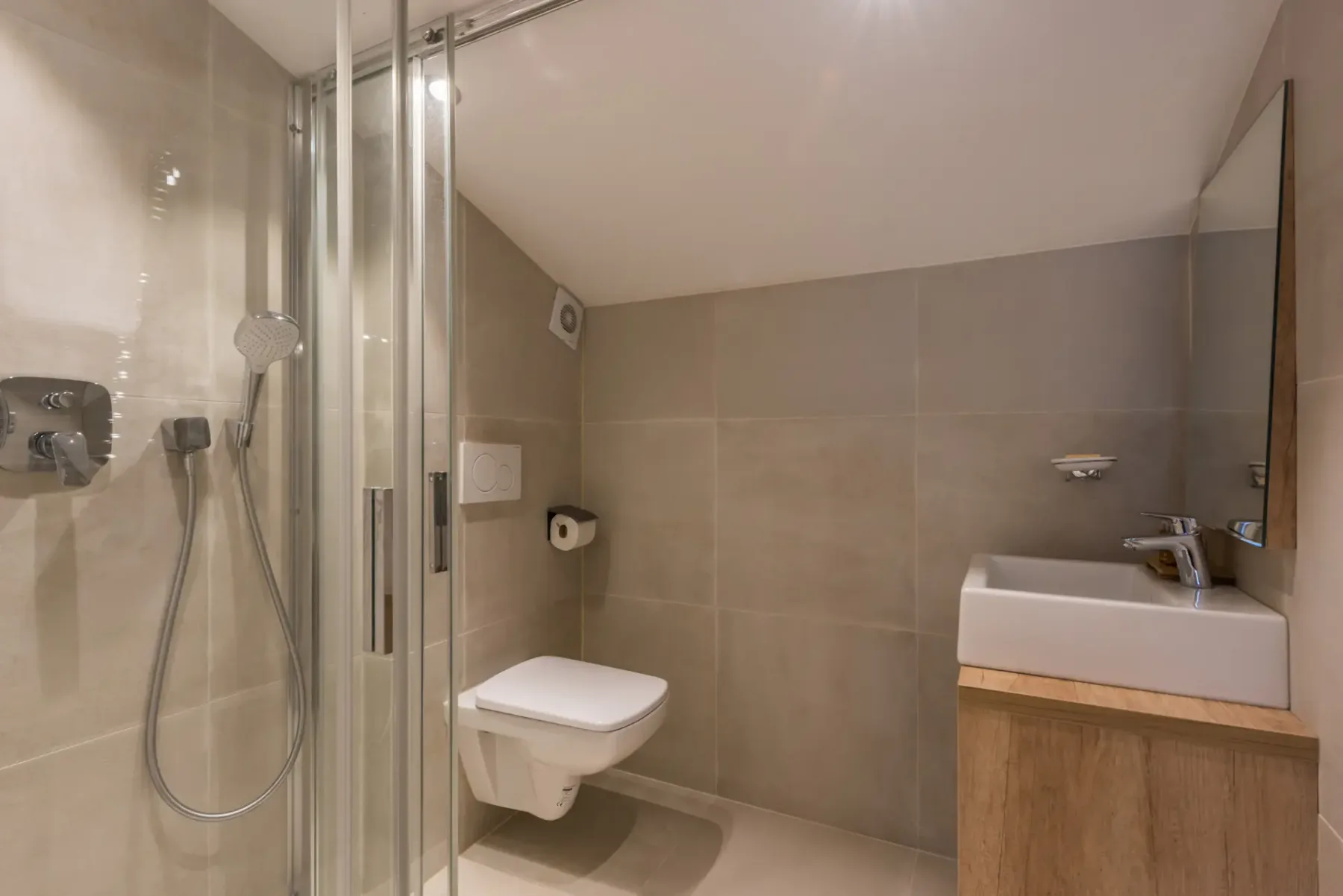 Un baño moderno con ducha y un inodoro suspendido.