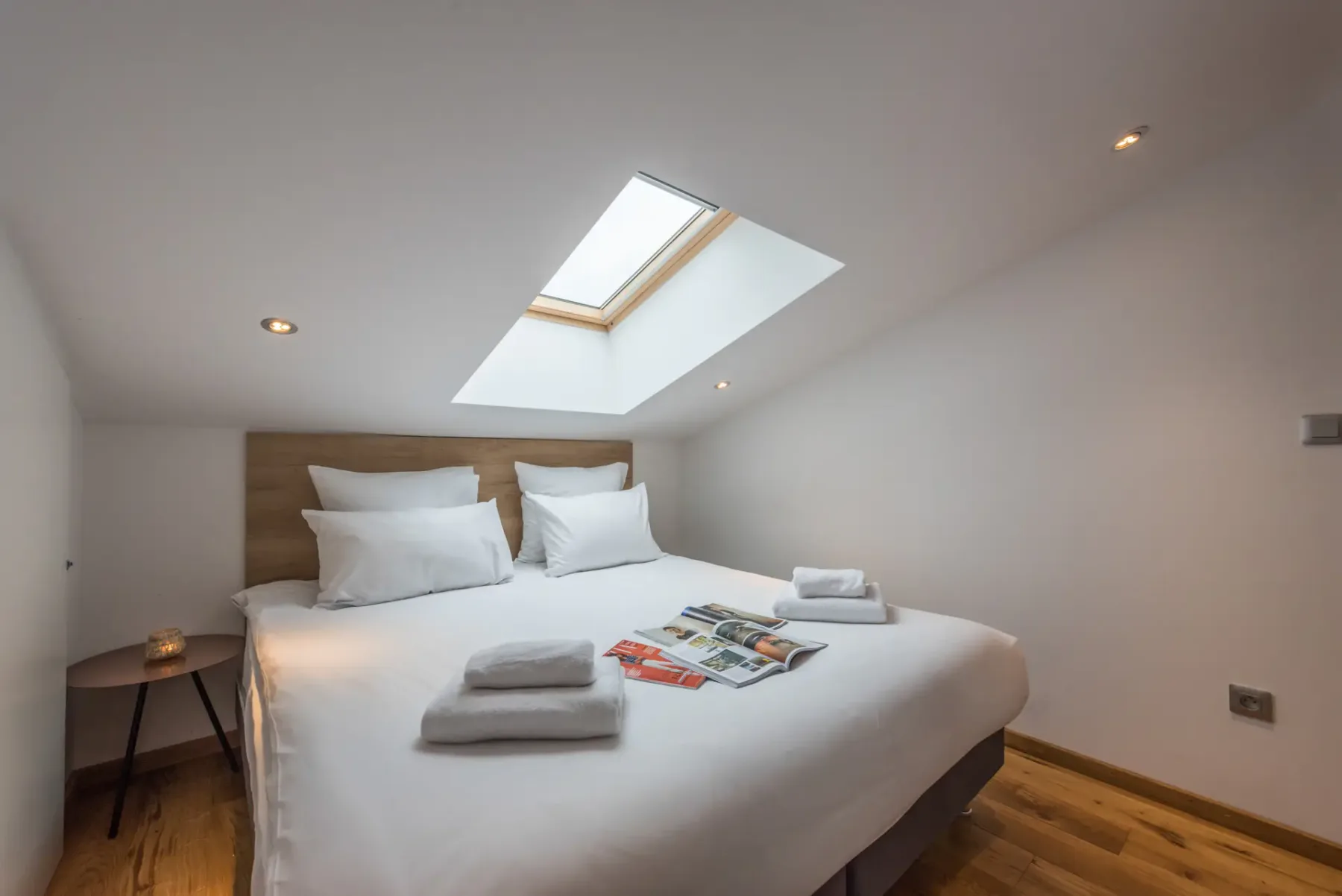 Un dormitorio luminoso con una cama doble bajo una claraboya.