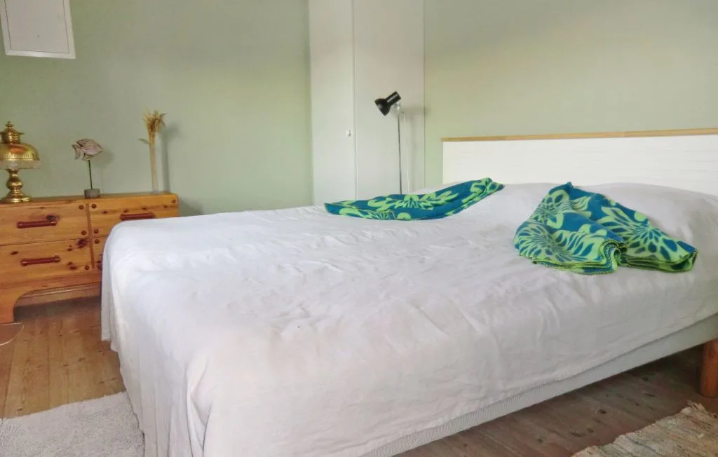 Un dormitorio con una cama grande cubierta con ropa de cama blanca y tela estampada verde.