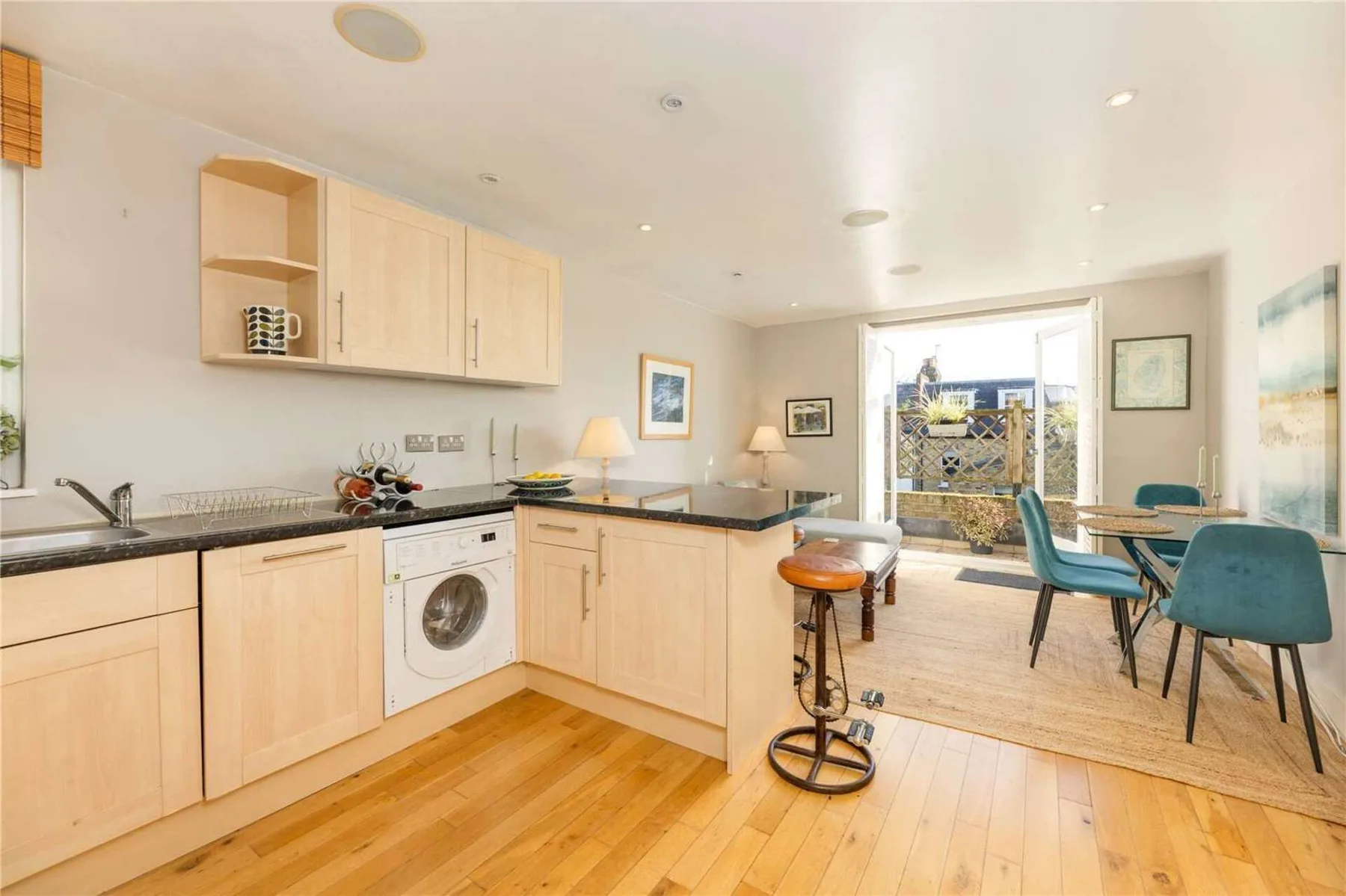 An open kitchen and dining area with light wood cabinets and blue seating.
