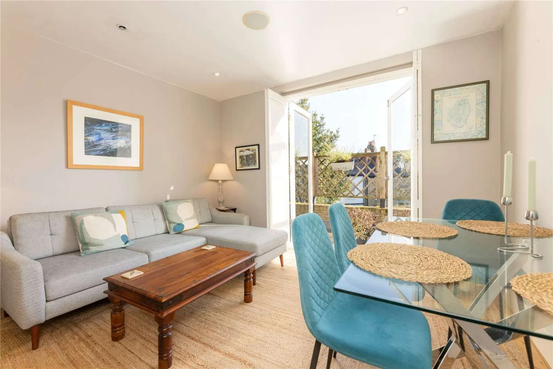 A living and dining area with a gray sofa and glass dining table.