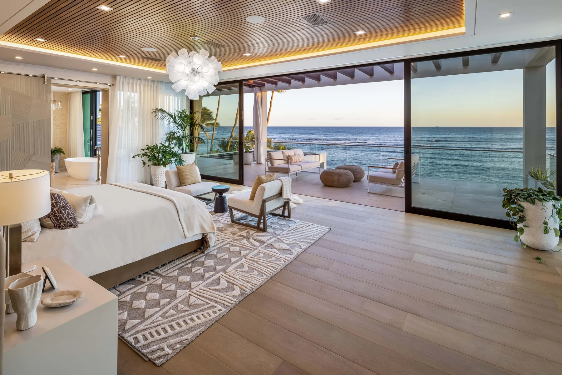 A bedroom opens onto a furnished terrace with a wide ocean view.