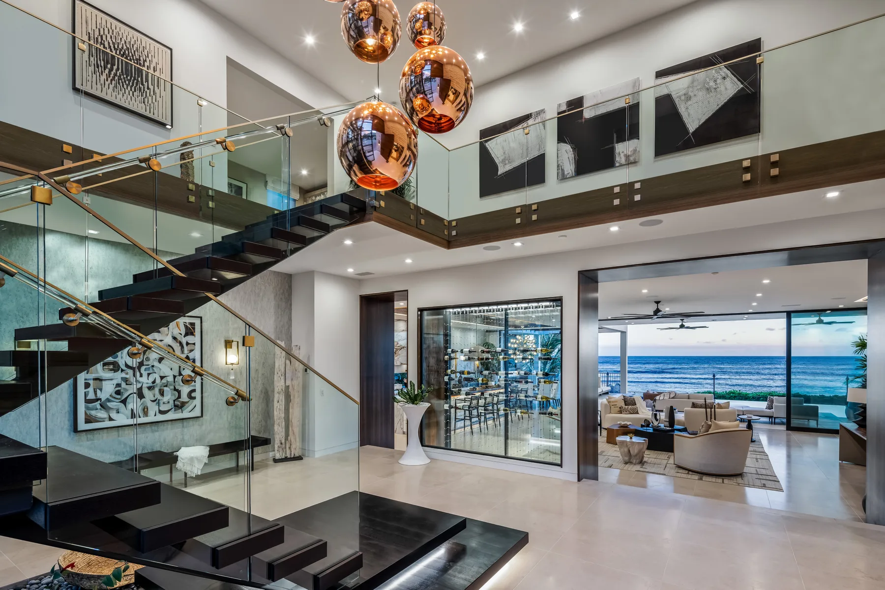 A modern living area opens toward a dining space and ocean views.