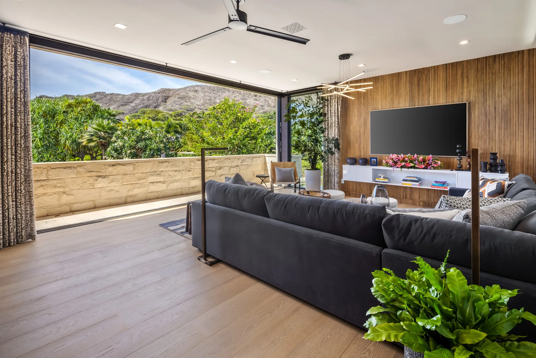 A modern living room with a large opening to a leafy outdoor view.