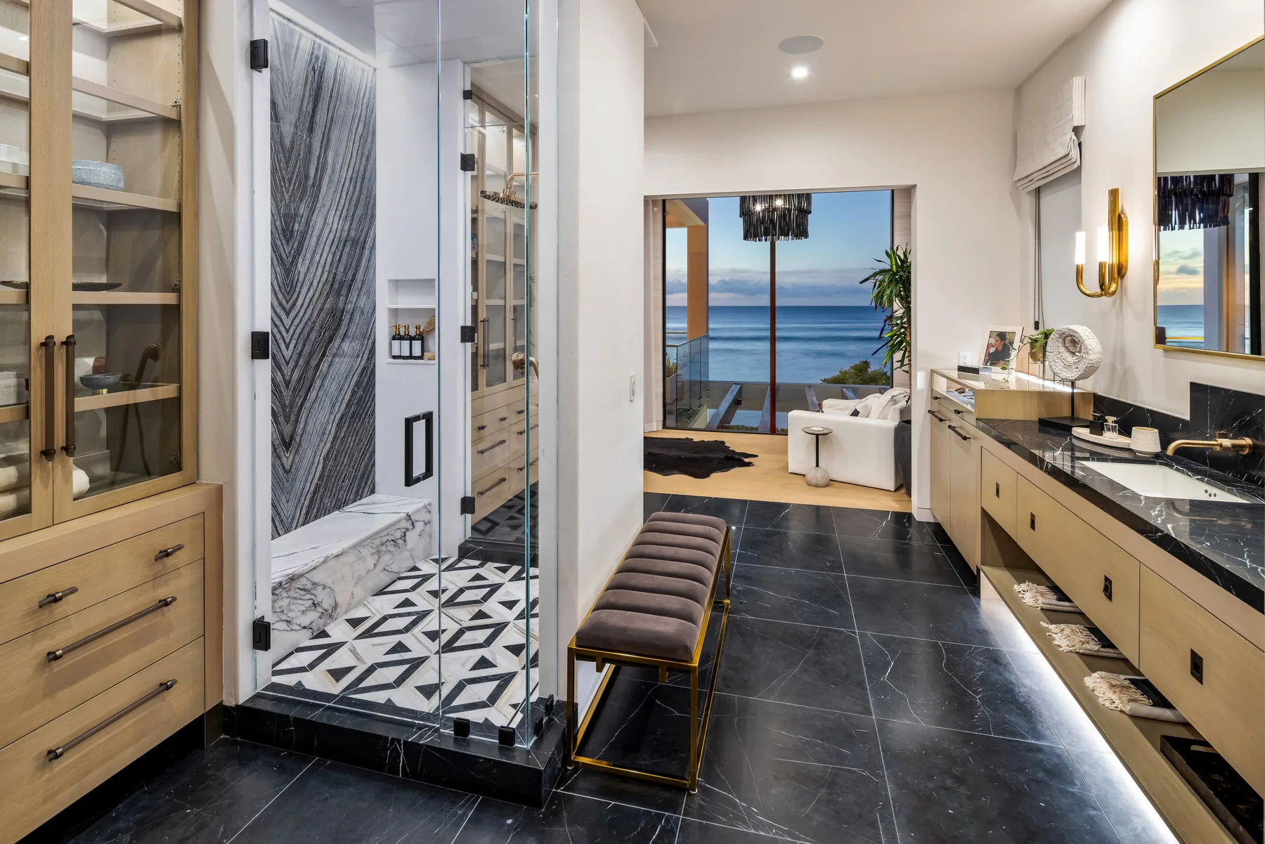 A modern bathroom with a glass shower, double vanity, and ocean view.