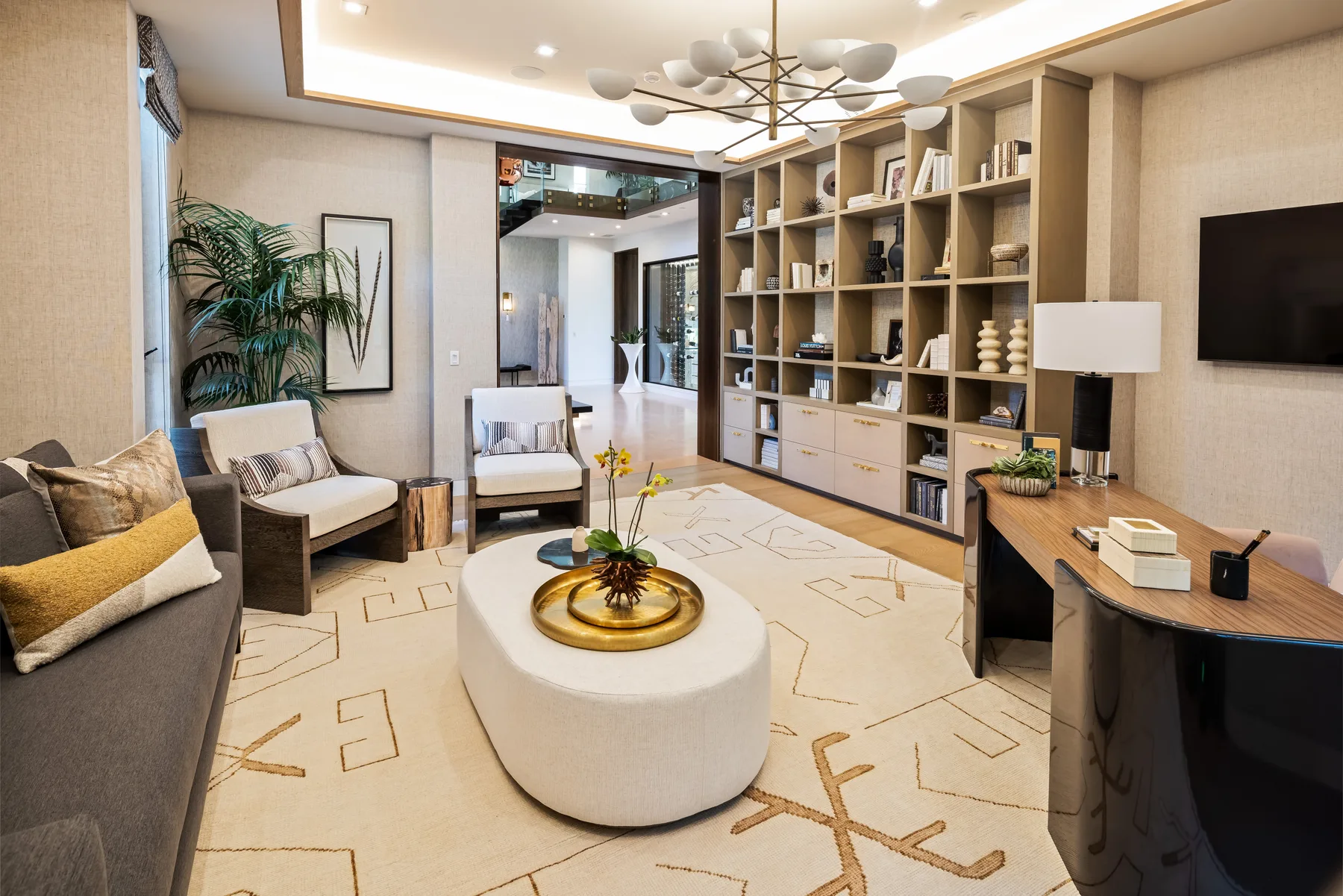 A bright living room with seating, a round coffee table, and built-in shelving.