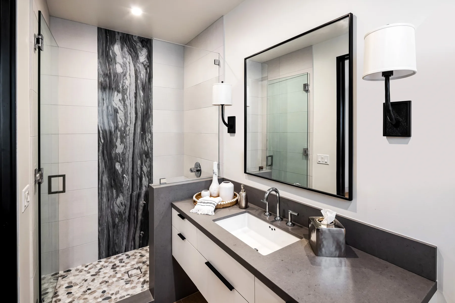 A modern bathroom vanity with a sink and a glass shower.
