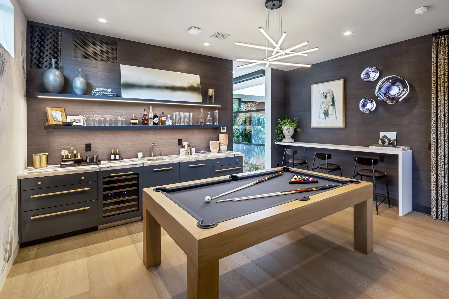 A billiards room with a pool table and a bar counter along the wall.