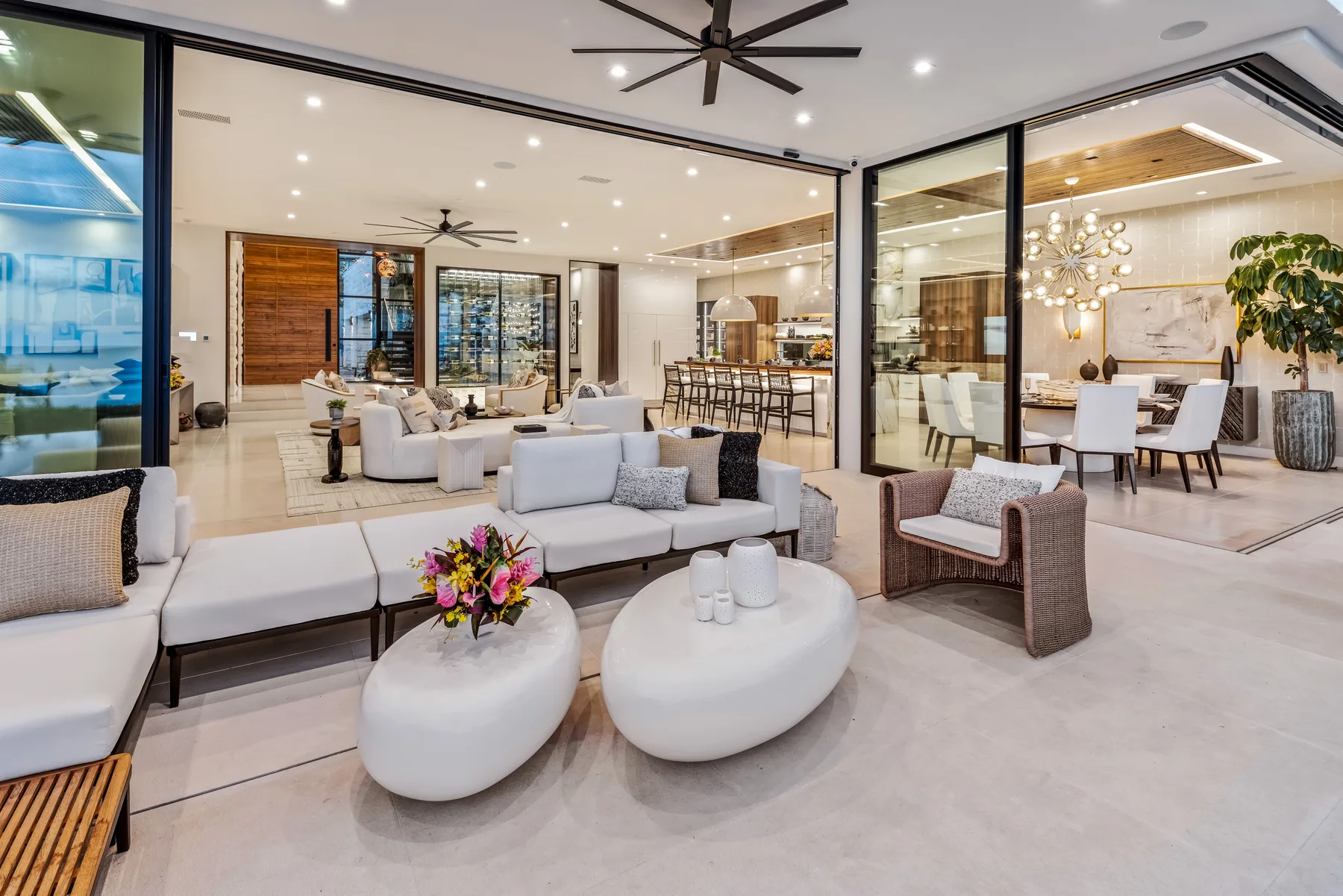 A bright open-plan living room with seating, a dining area, and large glass doors.