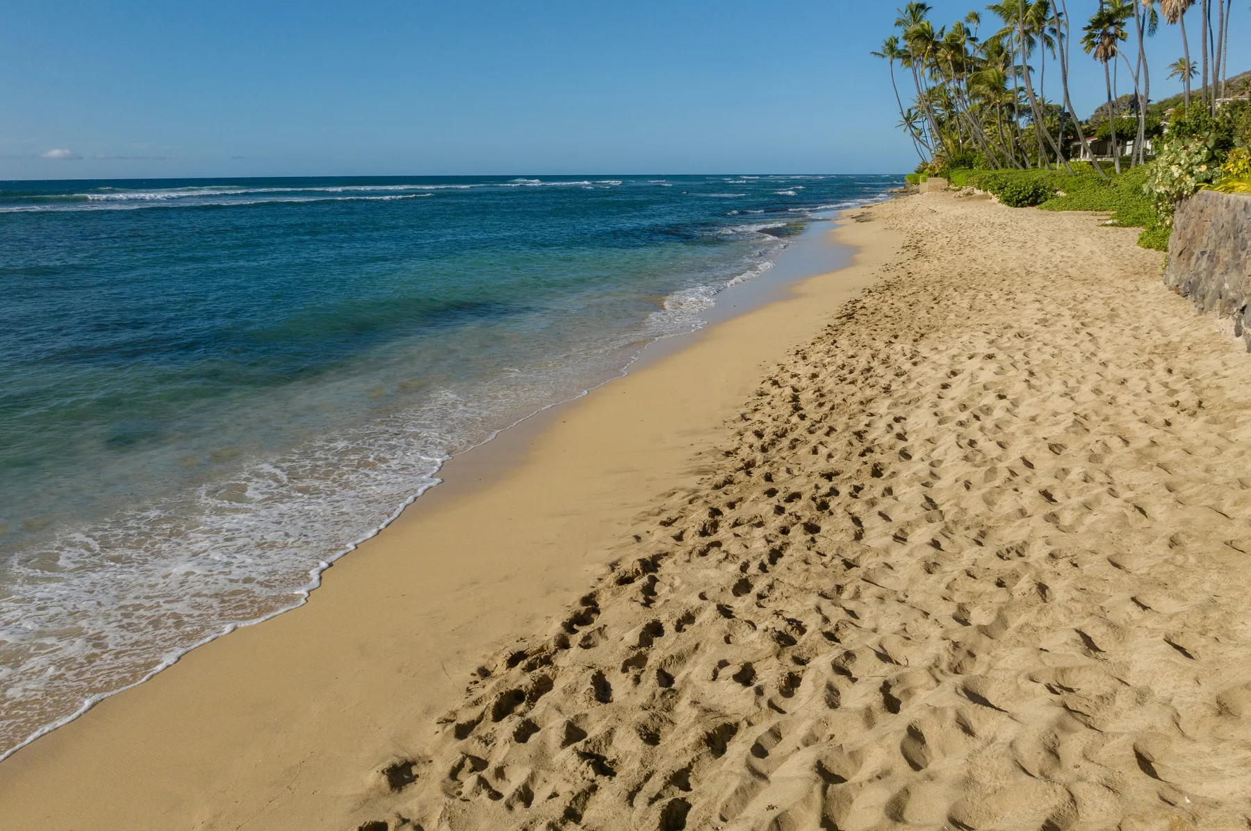 A sandy beach borders the blue ocean beneath a clear sky.