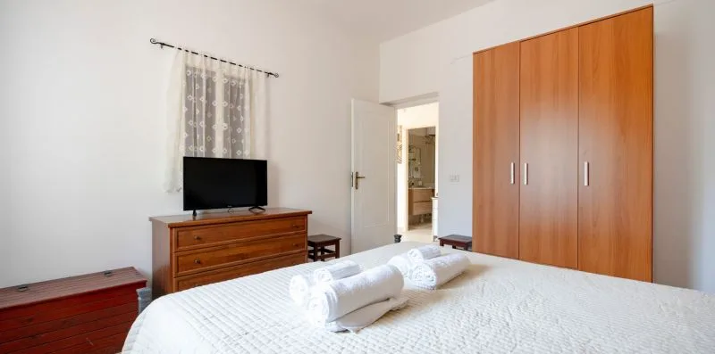 A bedroom with a bed, wooden dresser, and large wardrobe.
