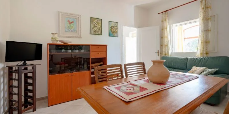 A dining area with a wooden table, patterned runner, and green seating.