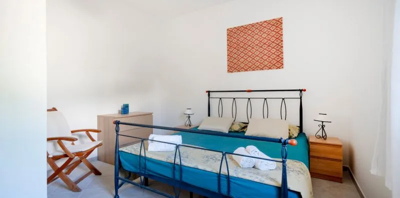 A bedroom with a metal bed, wooden bedside tables, and patterned wall art.