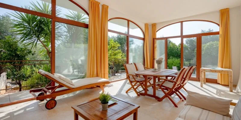 A bright sunroom with large arched windows and a dining table.