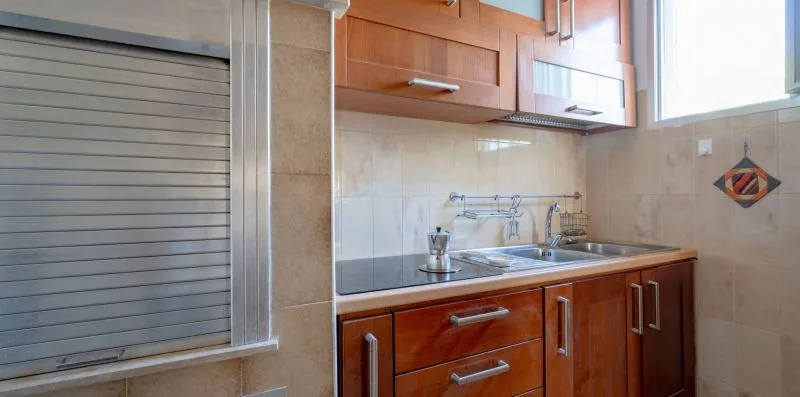 A kitchen counter with a sink sits beneath wooden cabinets.