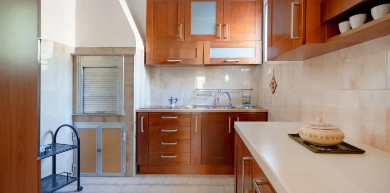 A kitchen with wooden cabinets, a sink, and a light-colored countertop.