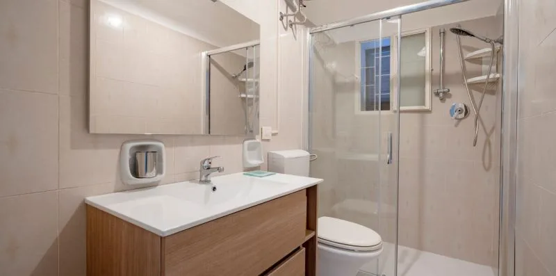 A bathroom with a vanity, mirror, toilet, and glass shower.