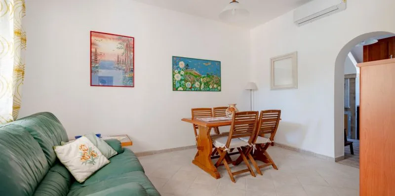 A living and dining area with green seating and a wooden table.